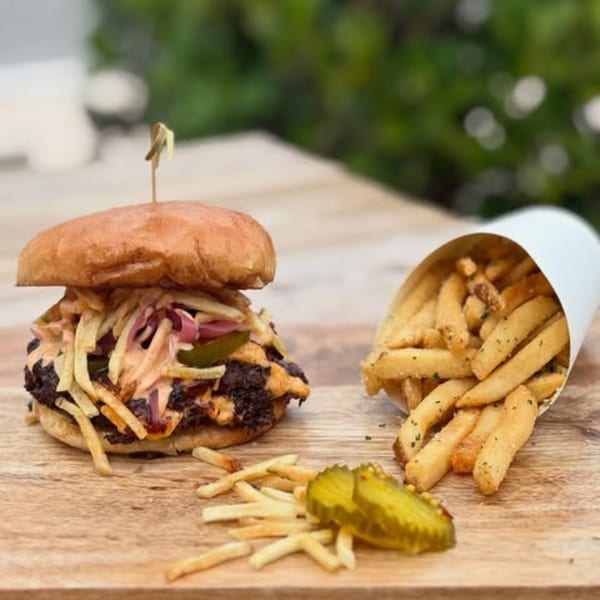 Island Burger with crispy fries, pickled onions, sauce, and a side of fries and pickles.